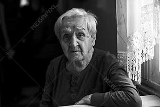 A tragic portrait of an old woman. Black and white photo.