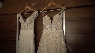 Embroidered wedding dresses decorated with sparkling stones hang on hangers in the room