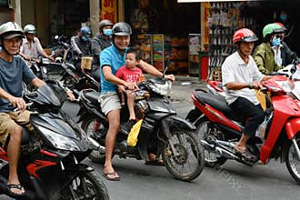 Motorbike rider with little child in front of bike at rush hour in the streets of Ho Chi Minh City, formerly Saigon, Vietnam