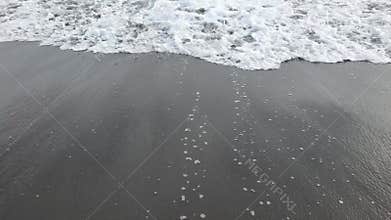 Sea foam reaching the shore in slow motion.