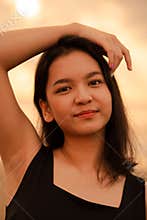 Beautiful Asian woman with a black shirt and black hair smiling with smooth skin near the beach