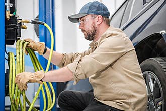 Car Mechanic Preparing to Inflate Vehicle Tires with Compressor