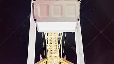 Cabins of Ferris wheel attraction move over night sky