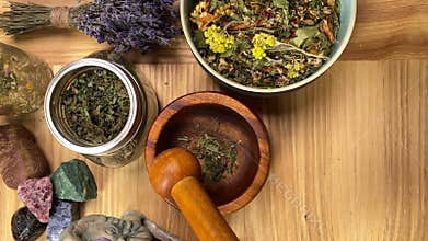 Table top view herbalist mixing dried herbs with mortar pestle indoors