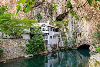 A clean underground river emerges from a cave near an mosque