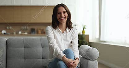 Home portrait of Latin 20s girl sitting on comfortable couch