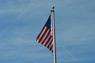 American Flag Waving on Flagpole Against Blue Sky