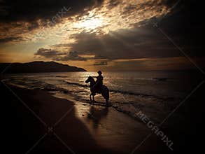 Horse rider on beach at sunset