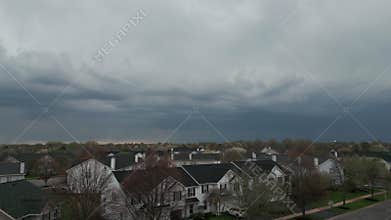 Dark stormy clouds forming on gloomy sky before heavy rainfall and lightning over suburban town area. Wide shot