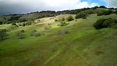 Flying over hiking trails on green California hills on cloudy rainy day