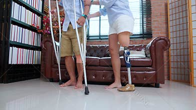 Young asian woman handicapper with leg and man sitting on sofa for relax in living room at home.