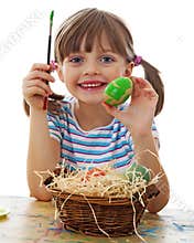 A happy little girl painting easter eggs
