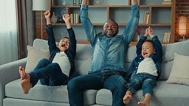 Excited African American happy family father and two siblings boys kids children fans watch TV sport game championship