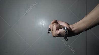 Close-up of An Asian man's hand is grabbing a large-sized chain bracelet and clutching it tightly.
