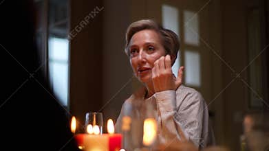 Low-angle view of elegant middle-aged family member sharing funny stories and joy during Christmas turkey dinner. People