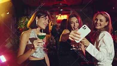 Elegant, happy, smiling young woman dancing in bar, drinking cocktail, recording video with phone. Christmas, winter