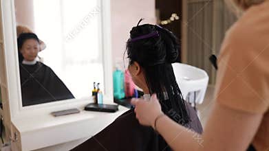 The hairdresser cuts the bangs of a asian girl with scissors in a hairdressing salon.