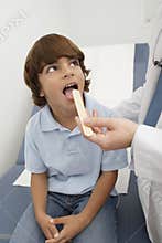 Examining Boy's Throat With Tongue Depressor