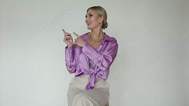 Video elegant, smiling blond woman in pink blouse and skirt showing and presenting empty space on right and left side