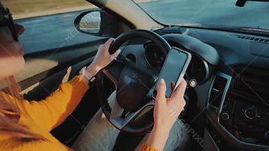 Young woman driver using mobile phone while driving car in motion, distracted driving, don't text and drive