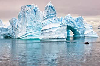 Iceberg in Antarctica, ice castle with Zodiac in front. Huge iceberg sculptured like fairytale castle