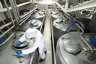 Worker closing industrial process tank in plant