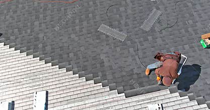 The roof of the house was installed with new shingles by a construction worker