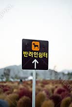 Vertical shot of a black square sign with a dog icon and Korean pet shelter text