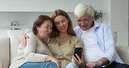 Happy adult daughter and elder parents watching media content
