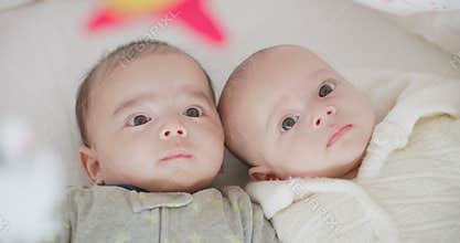 Cute little newborn twins babies boy and girl lying together in bed at home.