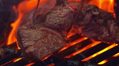 Grilling steaks on flaming grill