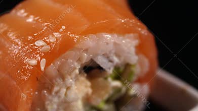 A piece of sushi with salmon in soy sauce.