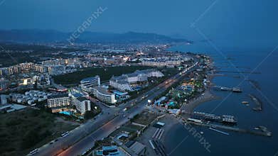 Stunning aerial sunset to night transition over Turkler in Alanya, Turkey. Alanya coastline,resorts,marina,hotels and city lights