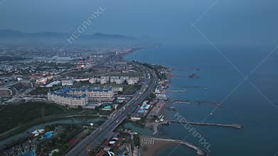 Stunning aerial sunset to night transition over Turkler in Alanya, Turkey. Alanya coastline,resorts,marina,hotels and city lights