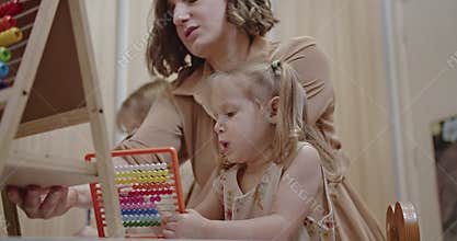 Family Time at Home: Mother Helping Daughters with Math Homework Using Abacus