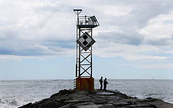 The silhouette of the two anglers trying their luck on the rocky inlet jetty near Ocean City, Maryland