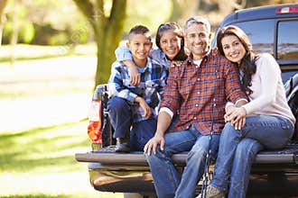 Family Sitting In Pick Up Truck On Camping Holiday