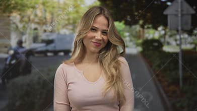 Woman head tilts on pedestrian street lined with leafy trees and parked scooters; serenity warmth calm