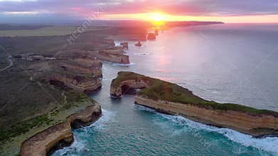 Drone view of the Twelve Apostles cliffs and ocean waves glowing under vibrant sunset skies