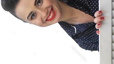 Charming pin-up girl playfully emerges from behind a folding screen