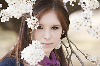 Young adult female looking through blossoms