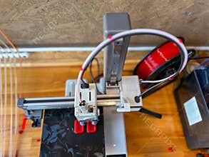 3d printer creating a prototype with red filament in a workshop