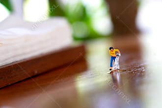 Miniature figurine pours water onto a reflective wooden surface