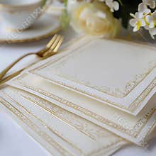 A set of four white cards with gold borders, arranged on a table
