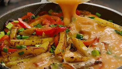 Pouring beaten eggs onto frying potatoes and vegetables closeup