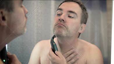 Young bearded man during grooming of beard using trimmer. Half face with a beard half shaved
