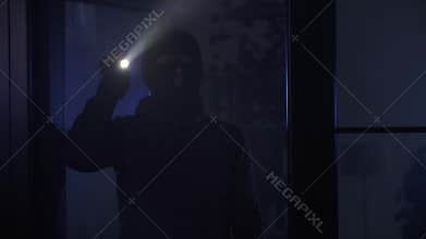 illegal entry into an apartment, man in balaclava with flashlight in his hands sneaks into room at night