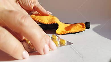 A woman\'s hand strokes a soft orange sleep mask lying on a white background