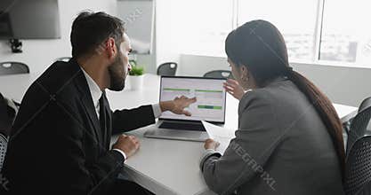 Two professionals discussing data displayed on laptop screen