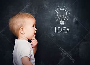 Baby child at the blackboard with chalk drawn bulb symbol ideas